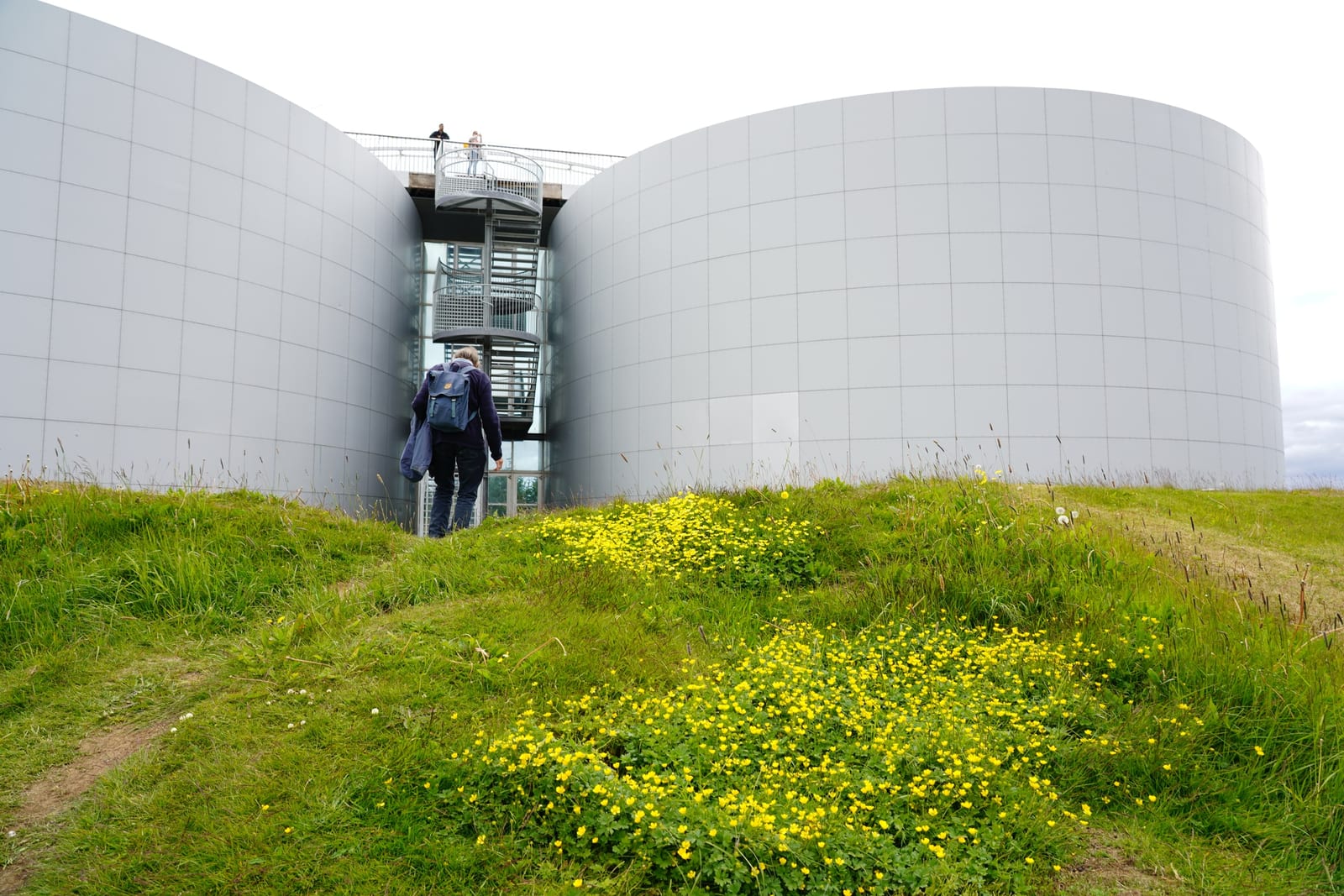 The Perlan dome and its surrounding hot-water tanks on Öskjuhlíð hill at golden hour, with Reykjavík's rooftops visible below.